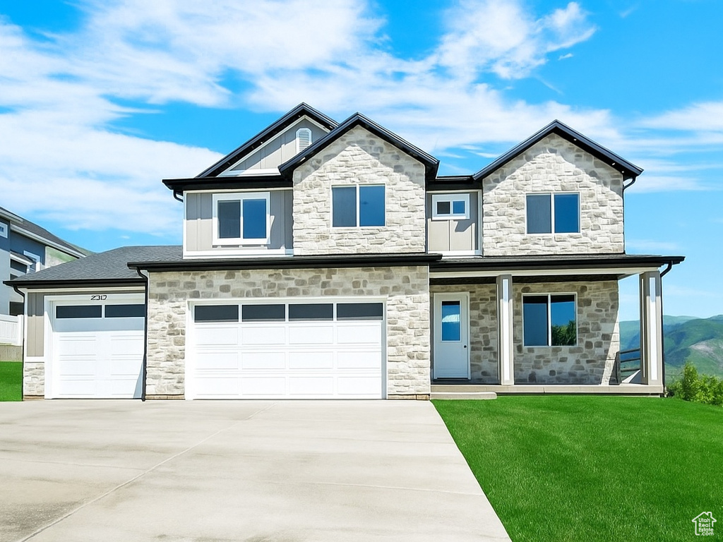 View of front of house with stone siding, concrete driveway, an attached garage, covered porch, and a mountain view