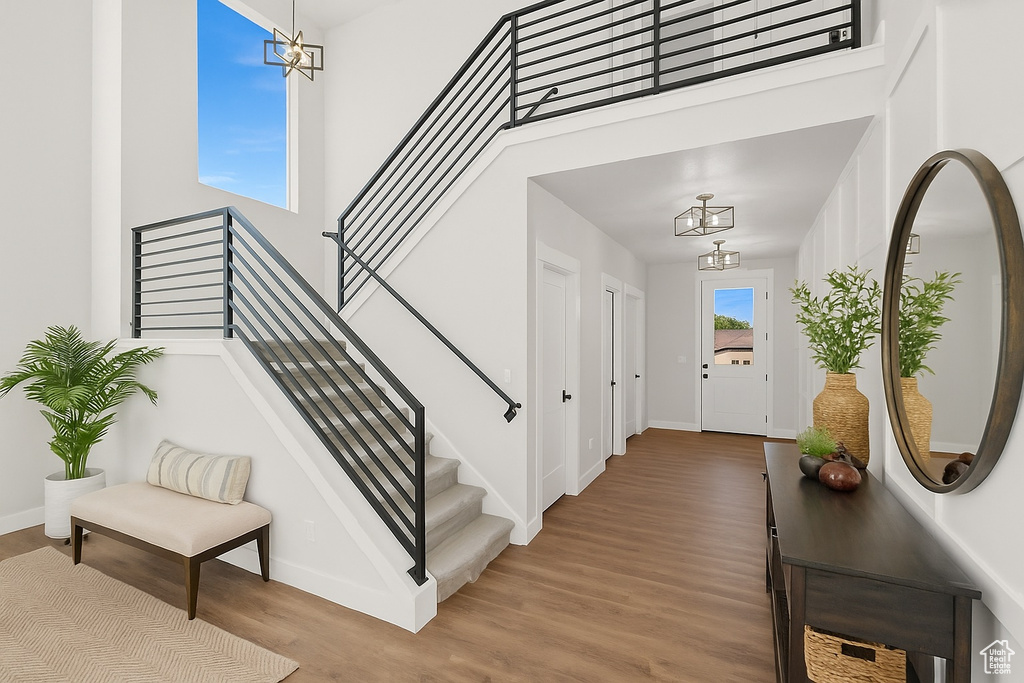 Entryway with a chandelier, wood finished floors, a towering ceiling, and stairway