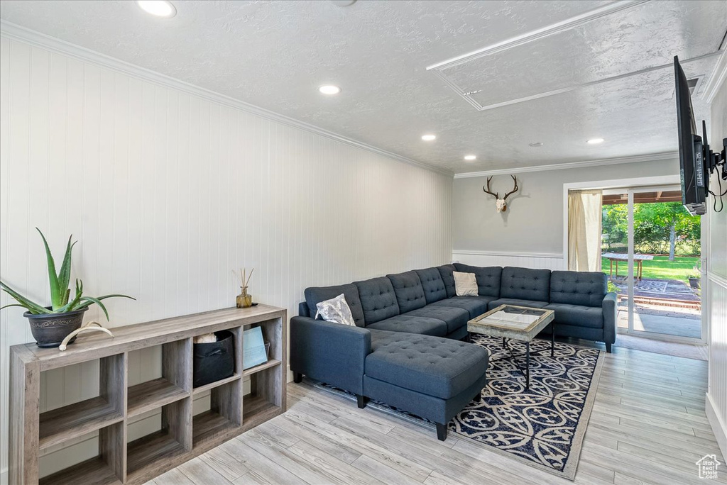 Living room with recessed lighting, ornamental molding, wood finished floors, attic access, and a textured ceiling