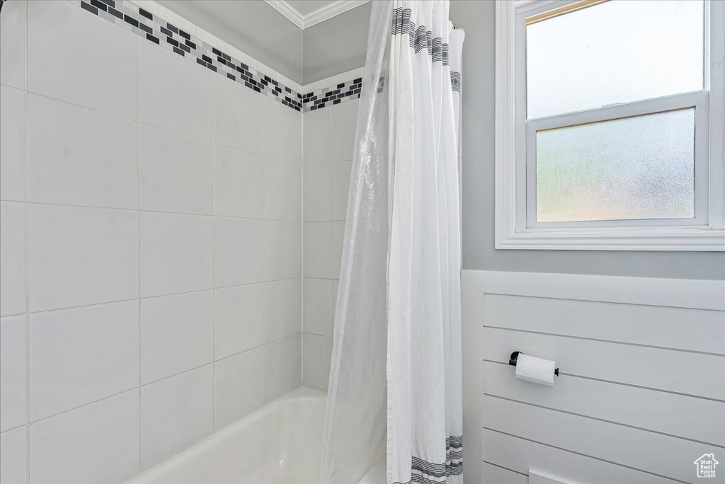 Bathroom with shower / bathtub combination with curtain and ornamental molding