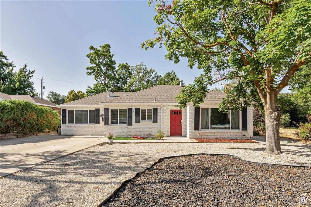 Single story home with brick siding, roof with shingles, and driveway