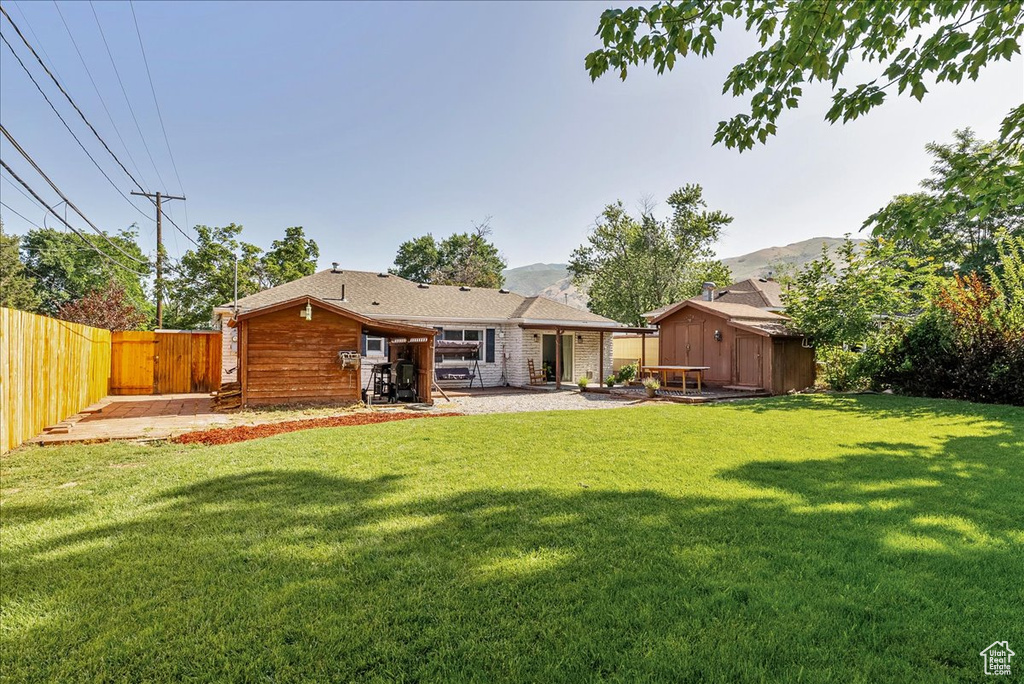 Back of house with a storage unit, a fenced backyard, a patio area, and a mountain view