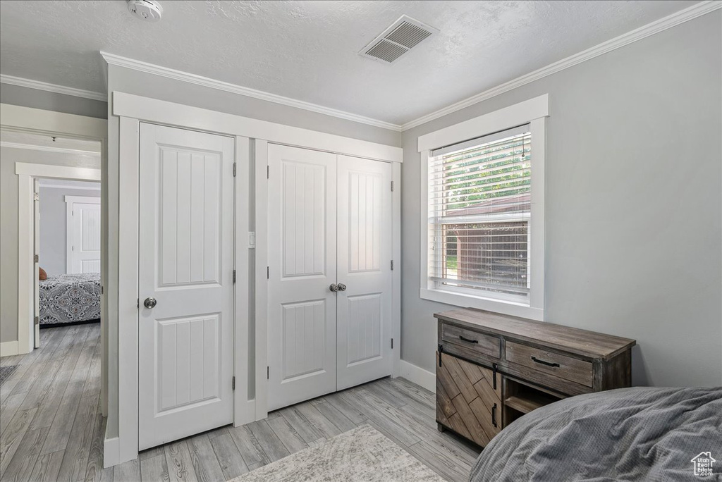 Bedroom featuring light wood-style flooring and crown molding