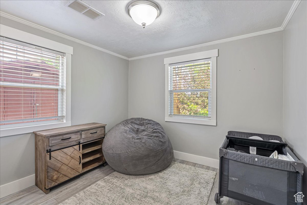 Bedroom with multiple windows, wood finished floors, crown molding, and a textured ceiling