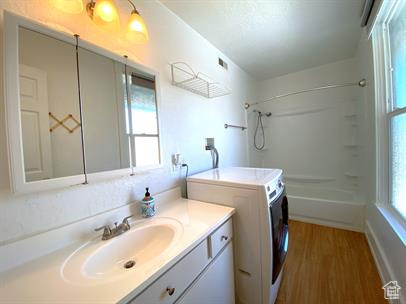 Full bathroom with vanity, shower / bath combination, washer and clothes dryer, and wood finished floors