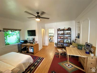 Bedroom featuring an office area, crown molding, and wood finished floors