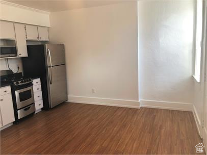 Kitchen with appliances with stainless steel finishes, dark countertops, and dark wood-style flooring