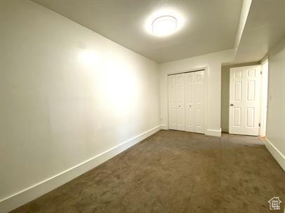 Unfurnished bedroom with dark carpet and a closet