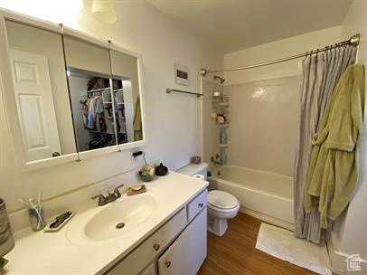Full bathroom with vanity, shower / bathtub combination with curtain, and wood finished floors