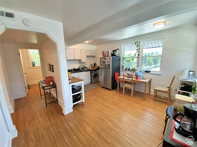 Kitchen with freestanding refrigerator, white cabinetry, healthy amount of natural light, and light wood finished floors