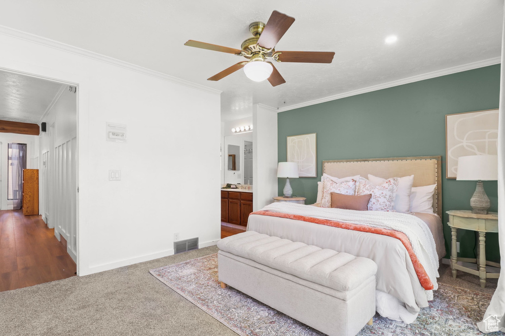 Bedroom with ornamental molding, connected bathroom, ceiling fan, and carpet floors