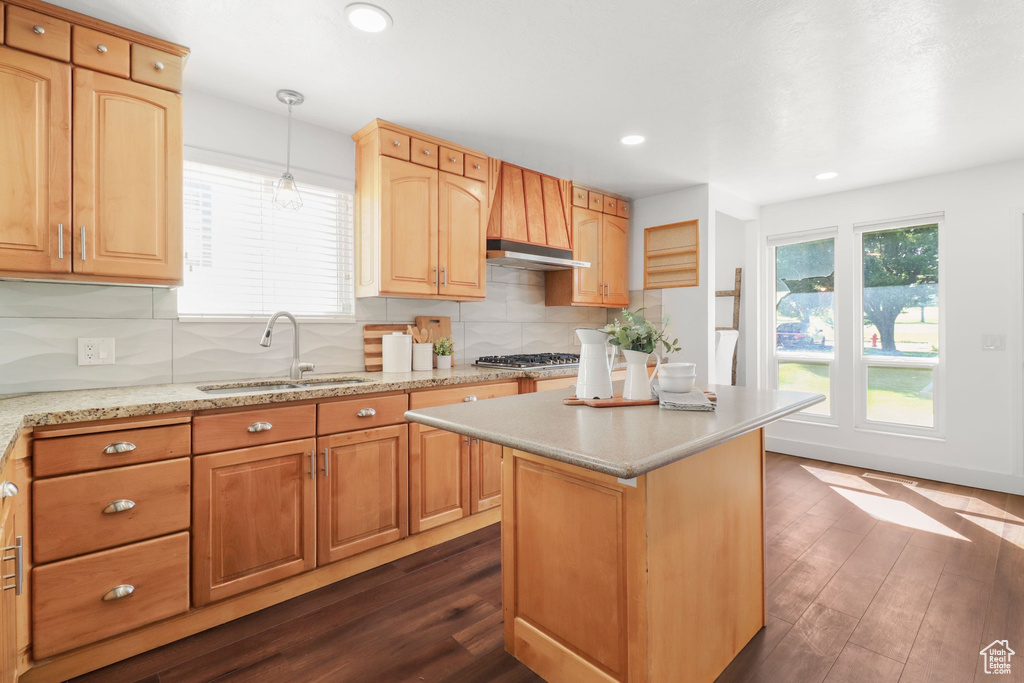 Kitchen featuring dark wood-style flooring, backsplash, premium range hood, recessed lighting, and a kitchen island