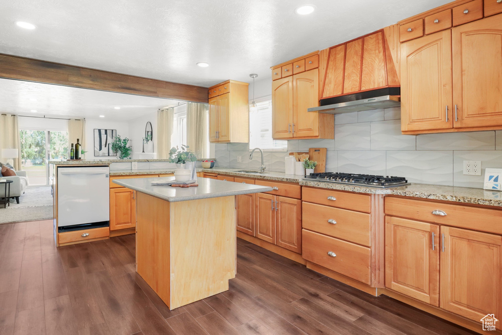 Kitchen featuring white dishwasher, dark wood-style floors, stainless steel gas stovetop, a peninsula, and tasteful backsplash