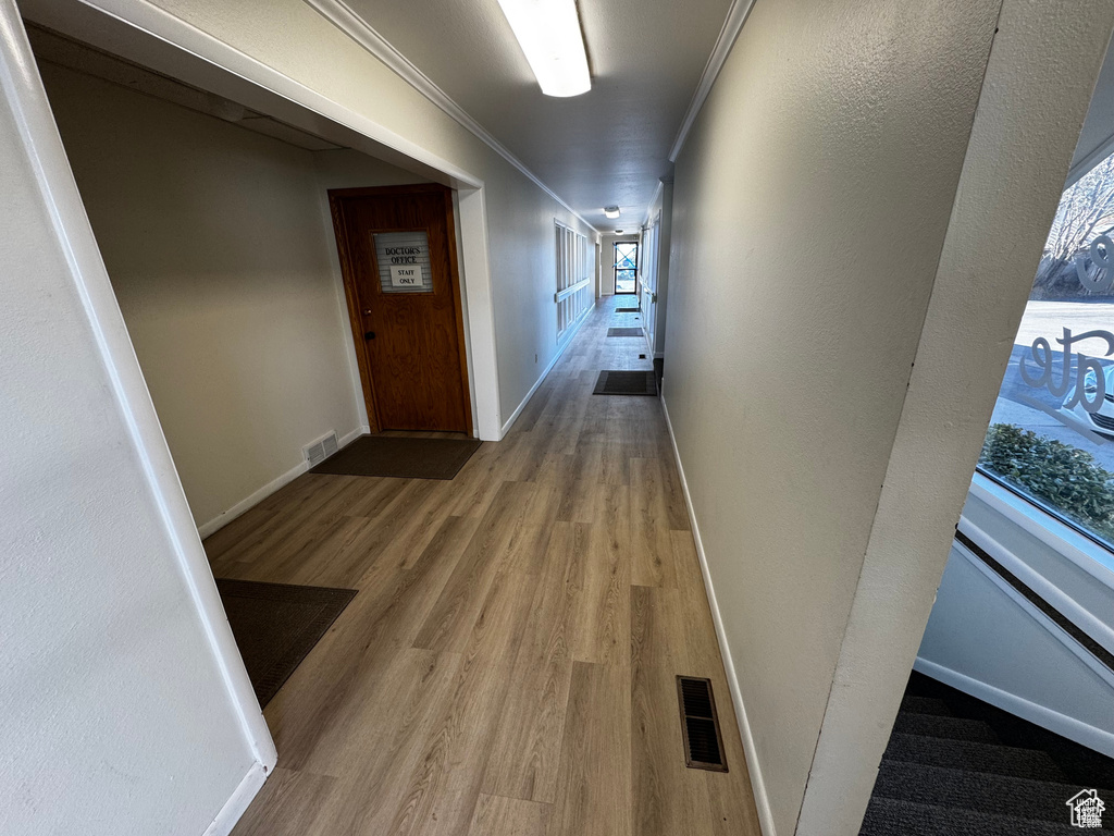 Corridor featuring wood finished floors and ornamental molding