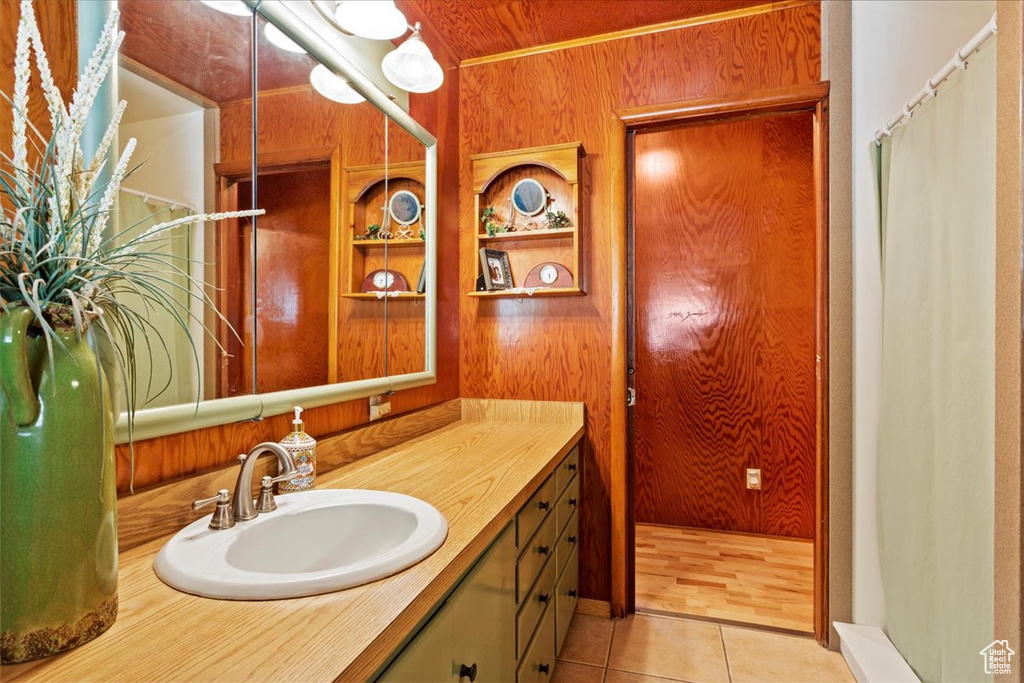 Full bathroom featuring vanity, tile patterned floors, wooden walls, and curtained shower