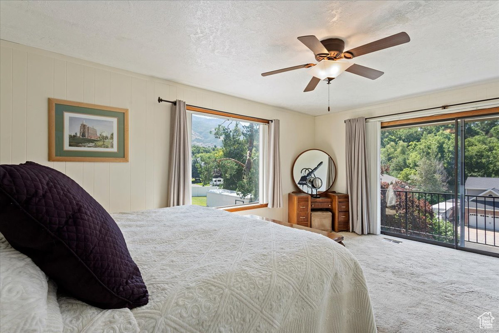 Bedroom with access to exterior, multiple windows, carpet, a textured ceiling, and ceiling fan