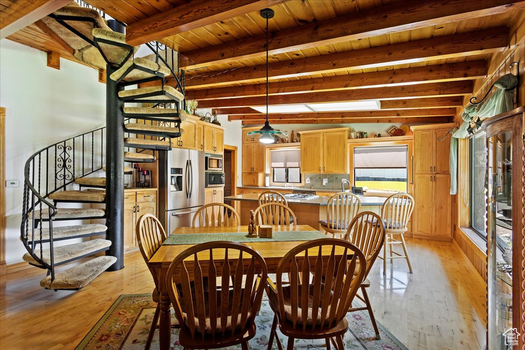 Dining room with light wood-style flooring, a wooden ceiling with exposed beams, and stairs