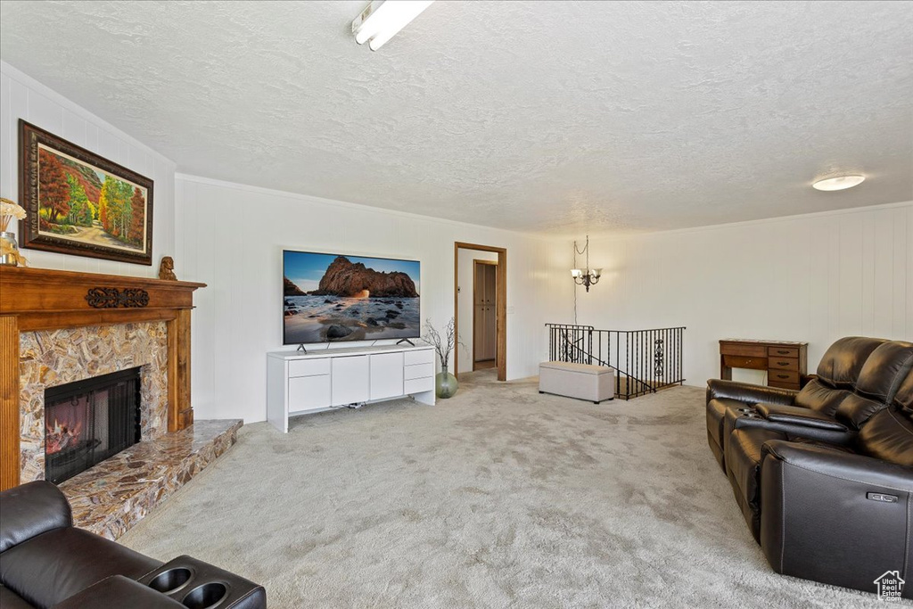 Carpeted living room featuring a textured ceiling, crown molding, and a fireplace