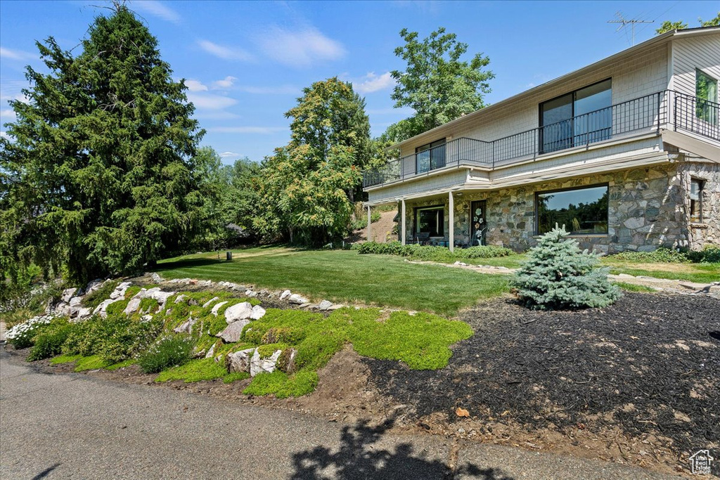 View of grassy yard featuring a balcony