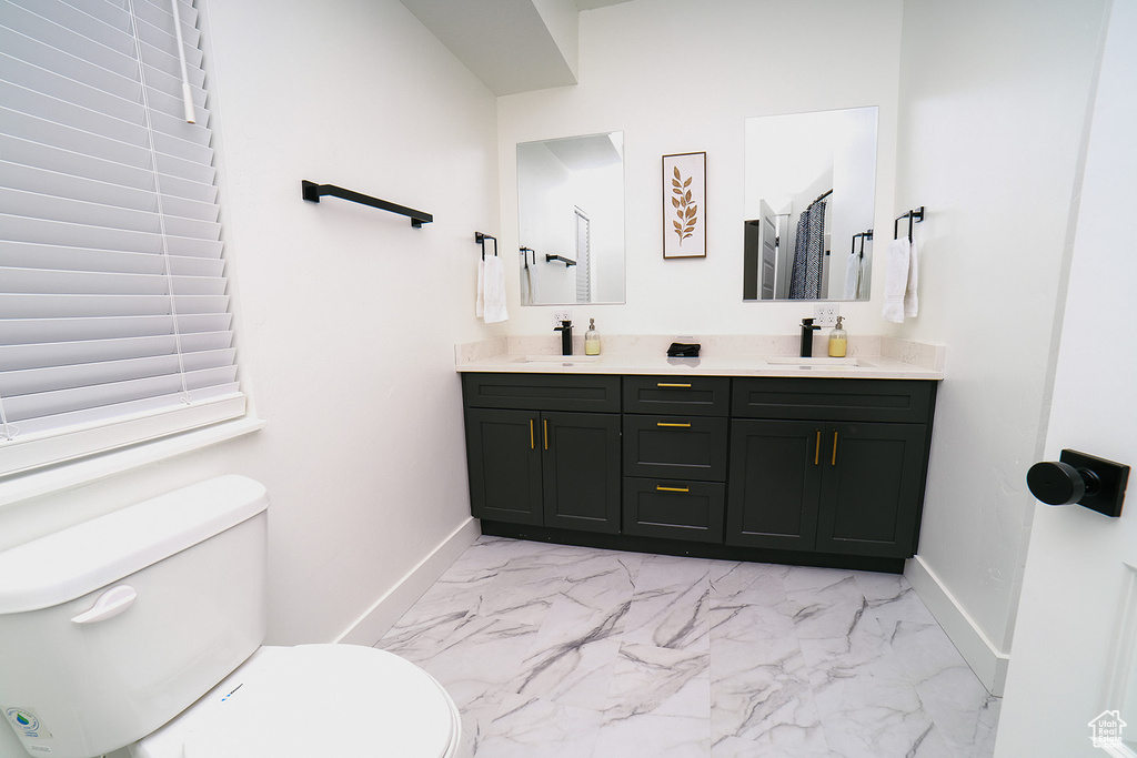 Bathroom with double vanity and marble look tiles