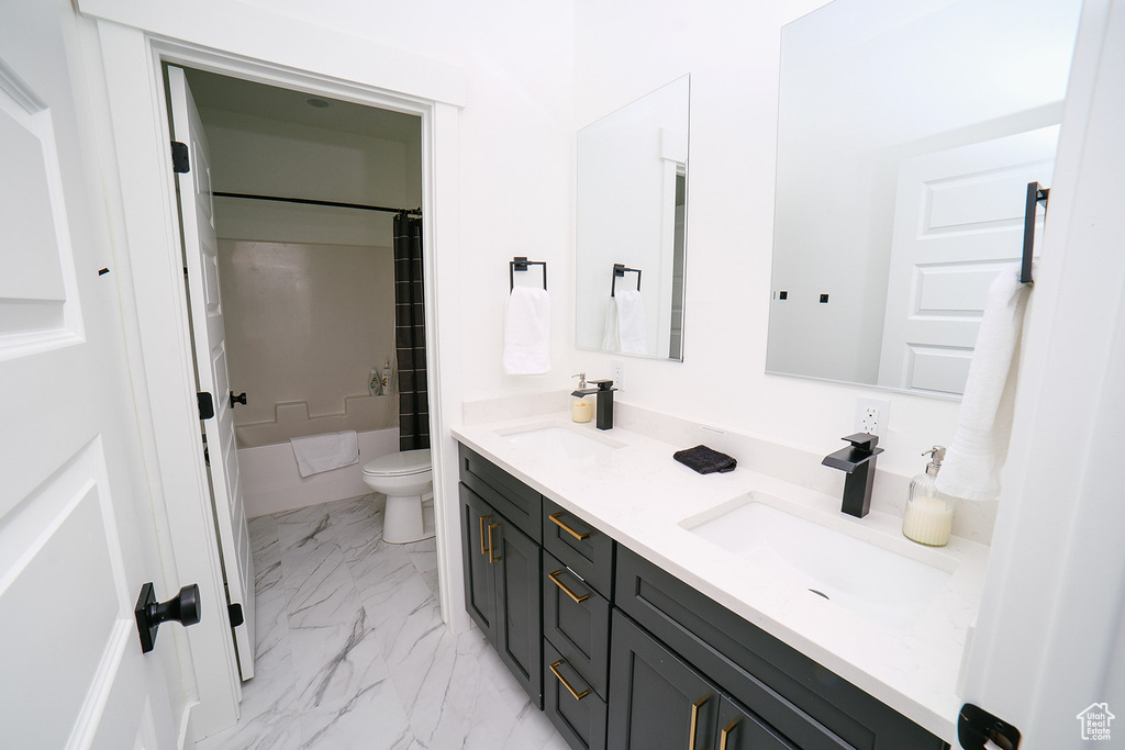 Bathroom featuring double vanity, marble look tiles, and shower / bathtub combination with curtain