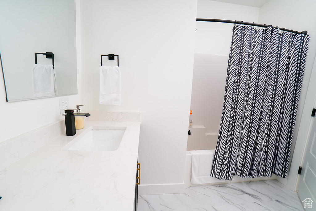 Bathroom featuring vanity, shower / bath combo with shower curtain, and marble look tiles