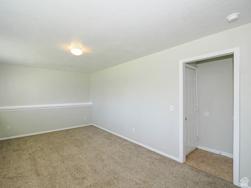 Unfurnished room featuring a smoke detector, a textured ceiling, and carpet flooring