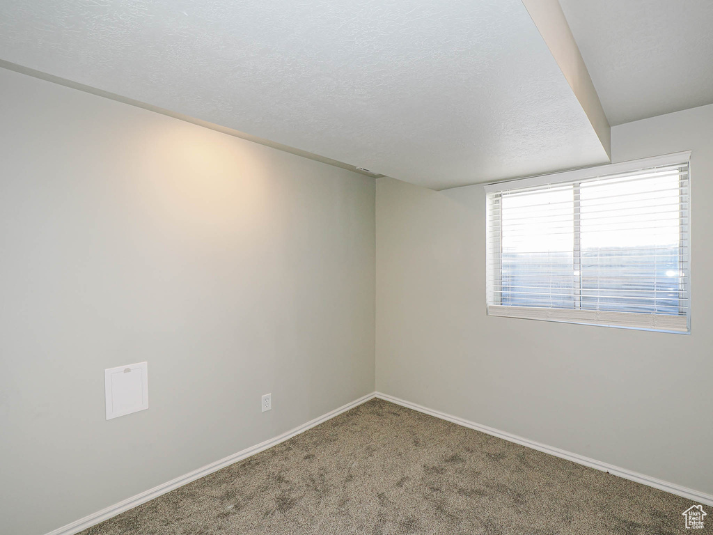 Empty room with carpet flooring and a textured ceiling