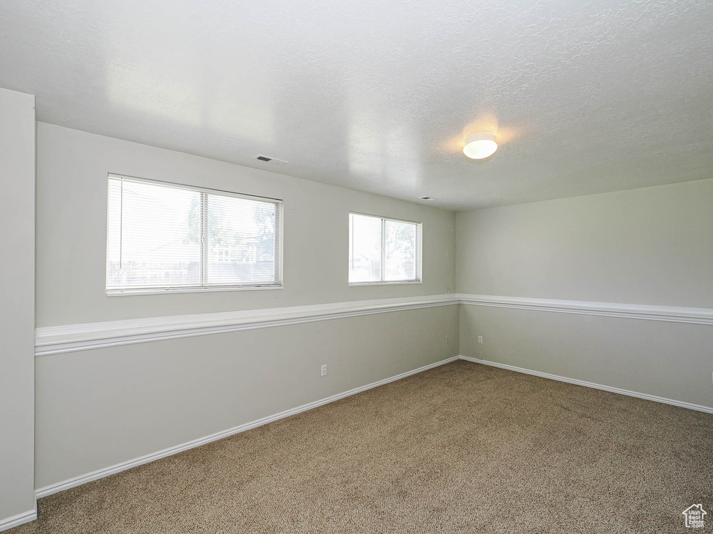 Carpeted empty room with baseboards and a textured ceiling
