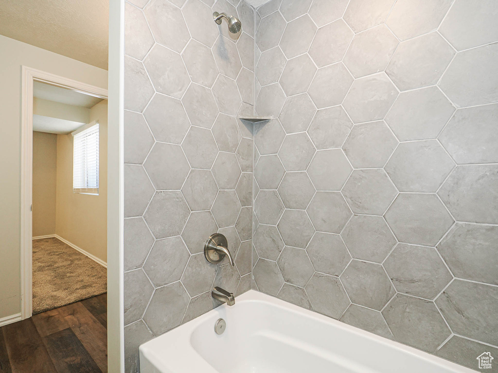 Bathroom with wood finished floors and bathing tub / shower combination