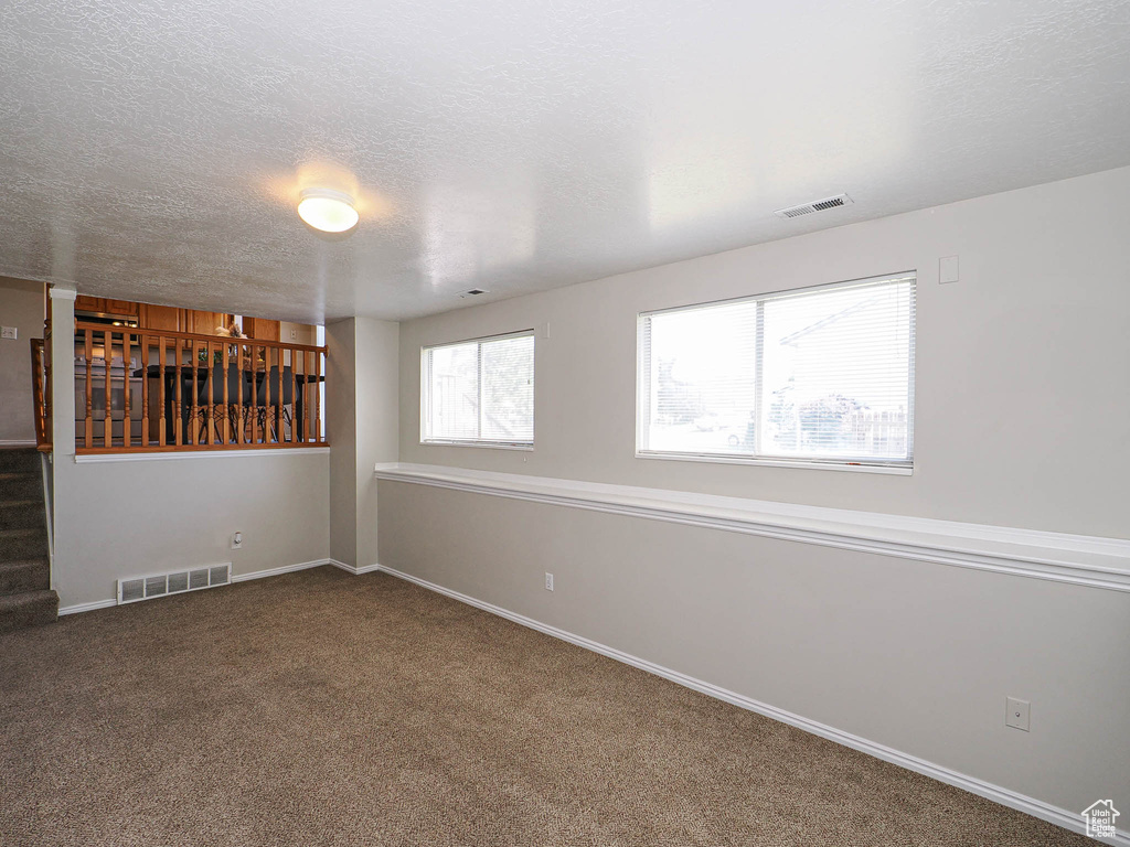 Carpeted spare room with stairway and a textured ceiling