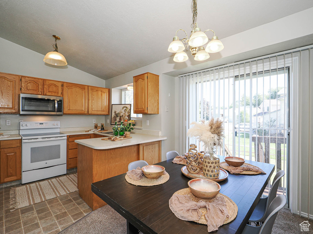 Kitchen with stainless steel microwave, white electric range oven, a chandelier, light countertops, and lofted ceiling
