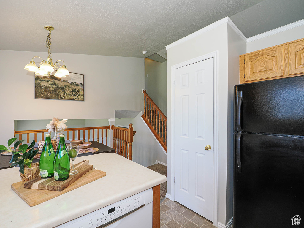 Kitchen with freestanding refrigerator, a chandelier, dishwasher, light brown cabinetry, and light countertops