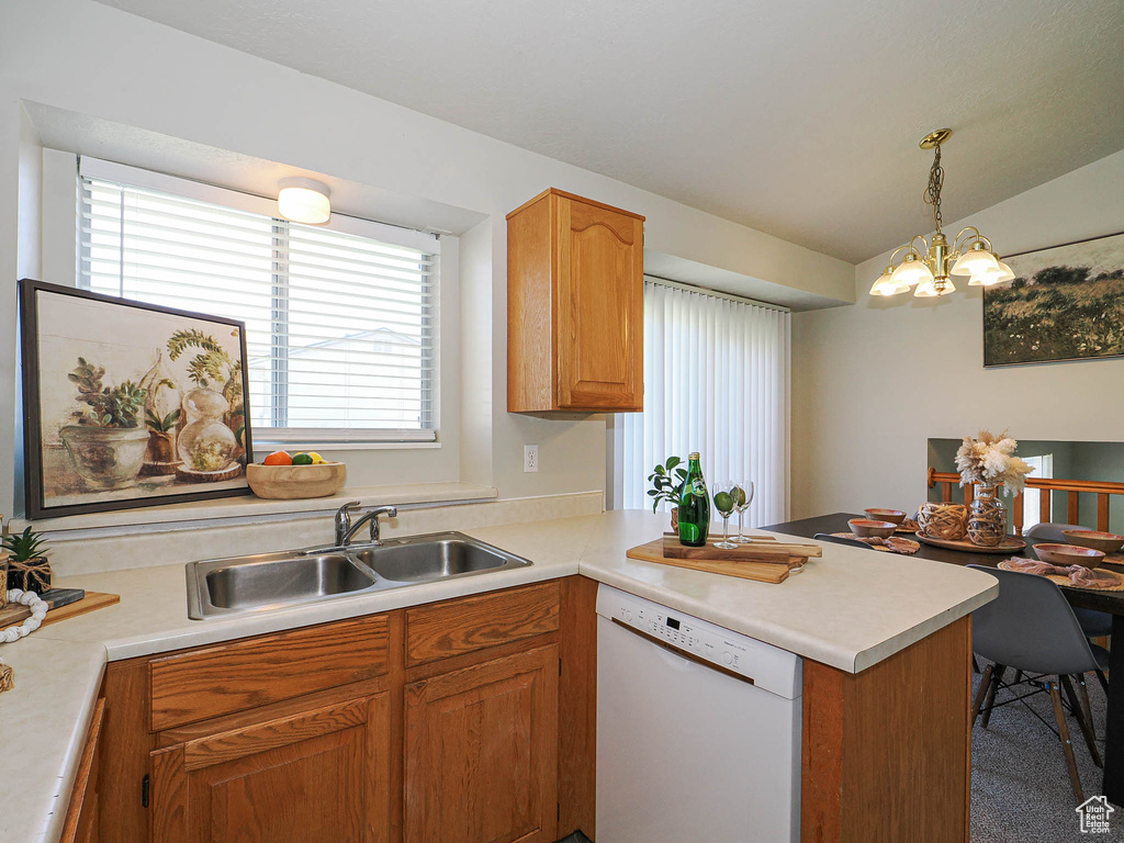 Kitchen featuring white dishwasher, a peninsula, light countertops, healthy amount of natural light, and vaulted ceiling