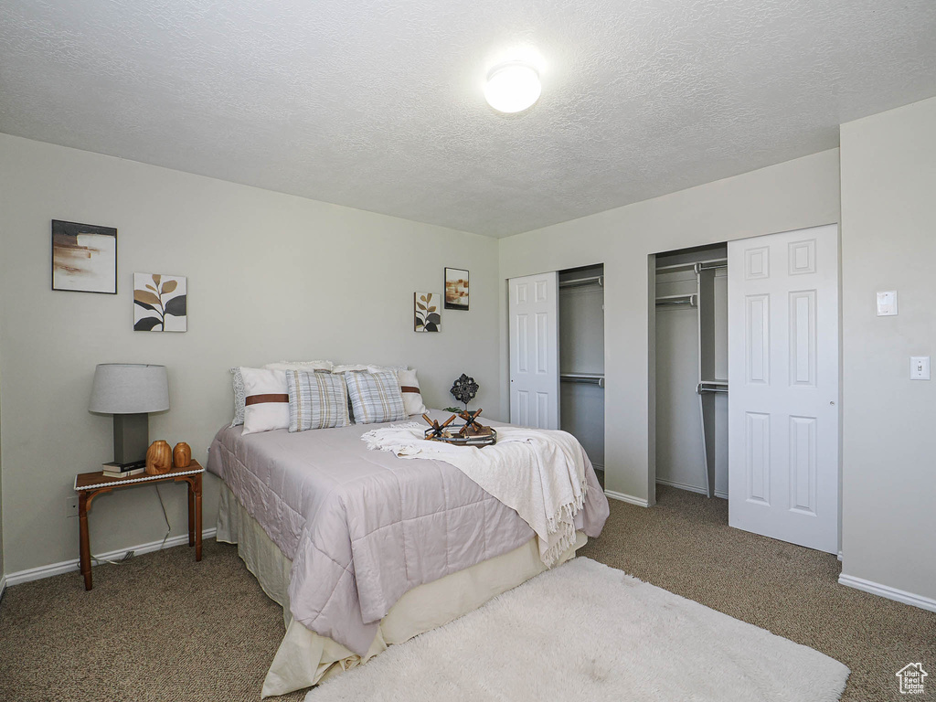 Bedroom with two closets, carpet, and a textured ceiling
