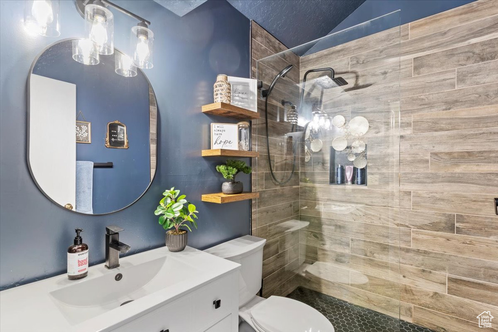 Full bath featuring vanity, walk in shower, and lofted ceiling