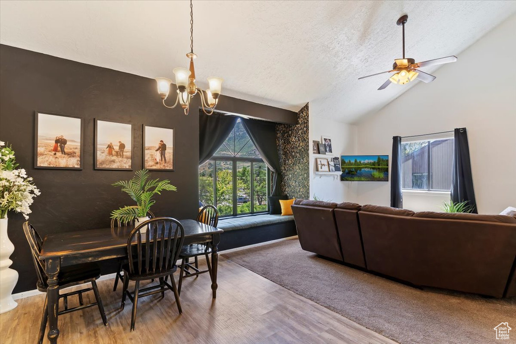Dining room with a chandelier, lofted ceiling, a textured ceiling, wood finished floors, and ceiling fan