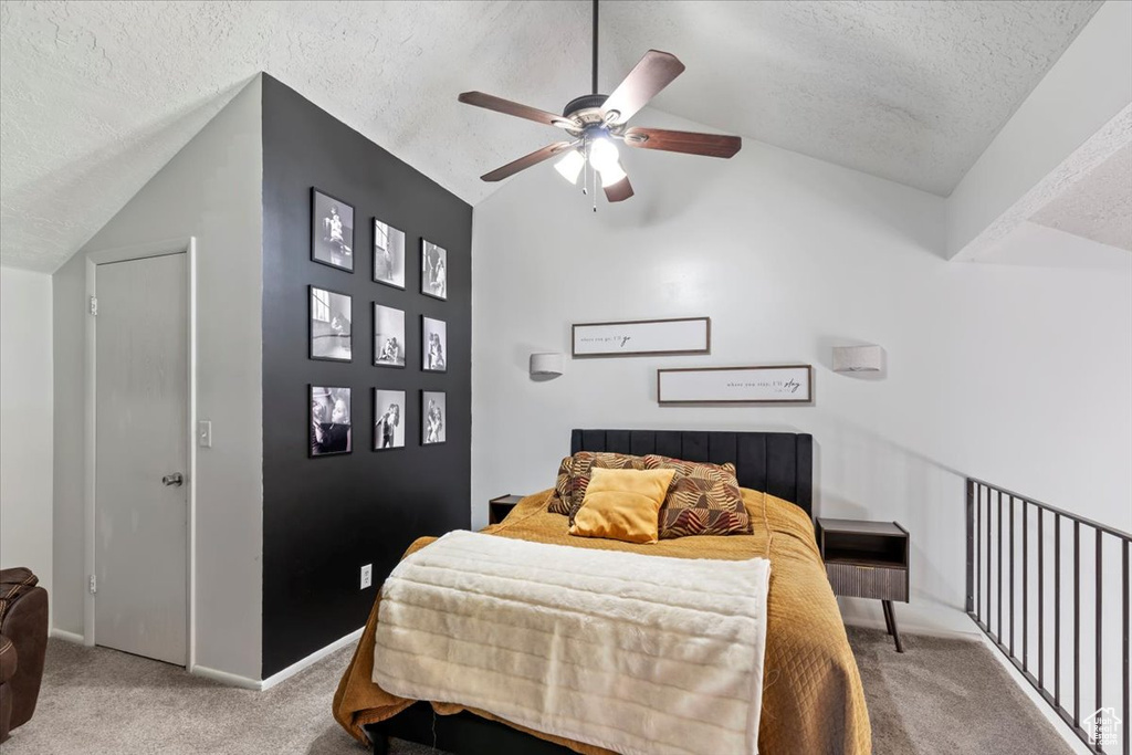 Carpeted bedroom featuring vaulted ceiling, a textured ceiling, and ceiling fan