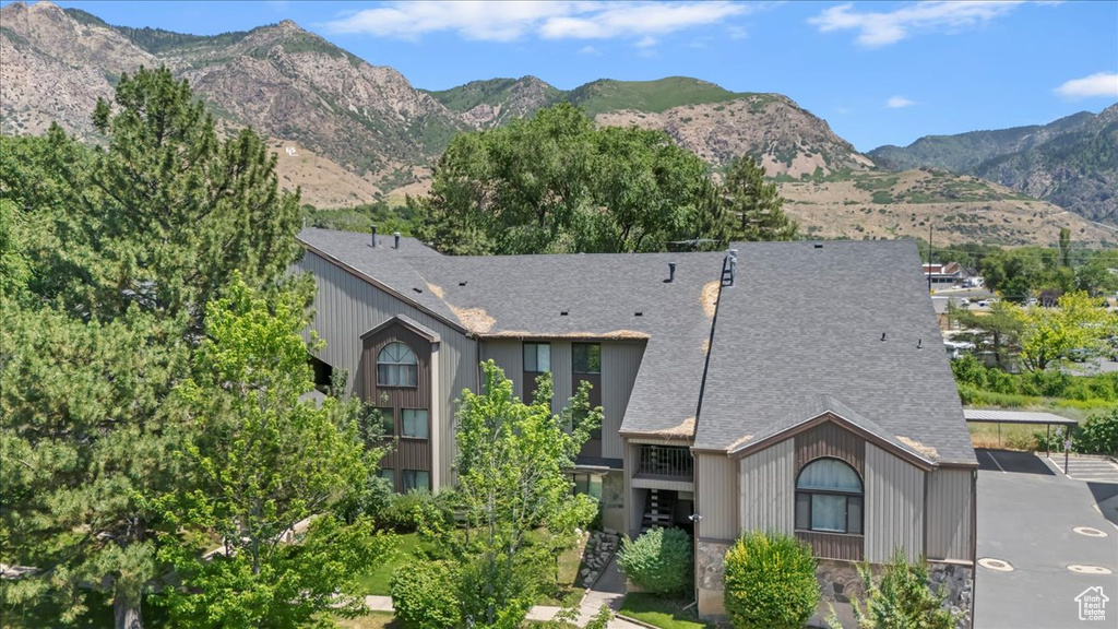 View of front of house with roof with shingles, a mountain view, and stone siding