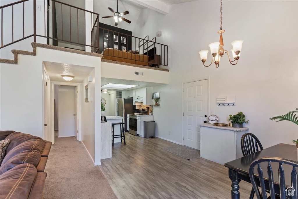 Living room featuring a ceiling fan, a chandelier, stairs, beamed ceiling, and high vaulted ceiling