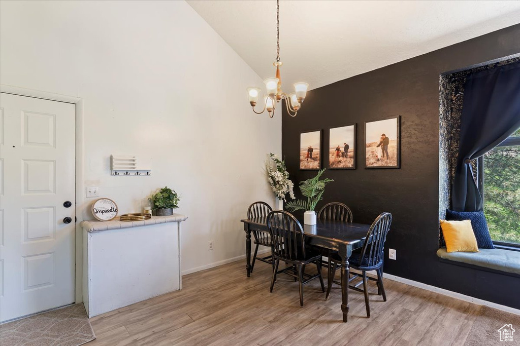 Dining area with a chandelier, light wood finished floors, and high vaulted ceiling