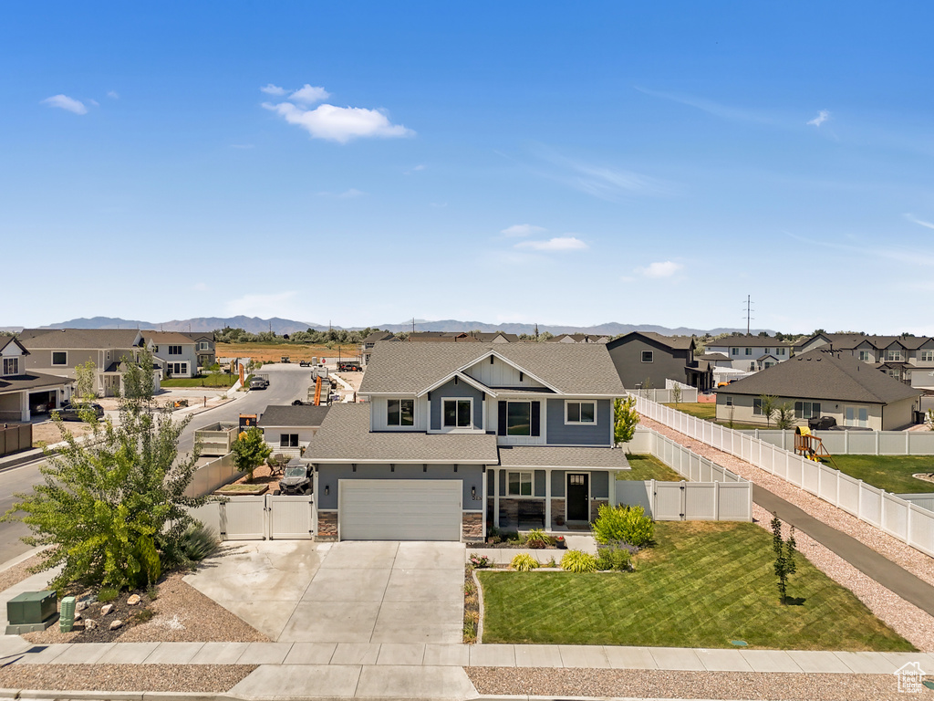 View of front of home featuring a residential view, concrete driveway, a gate, a mountain view, and a garage