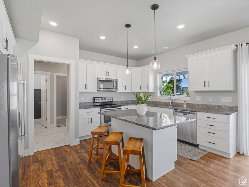 Kitchen featuring appliances with stainless steel finishes, a kitchen bar, white cabinetry, and recessed lighting