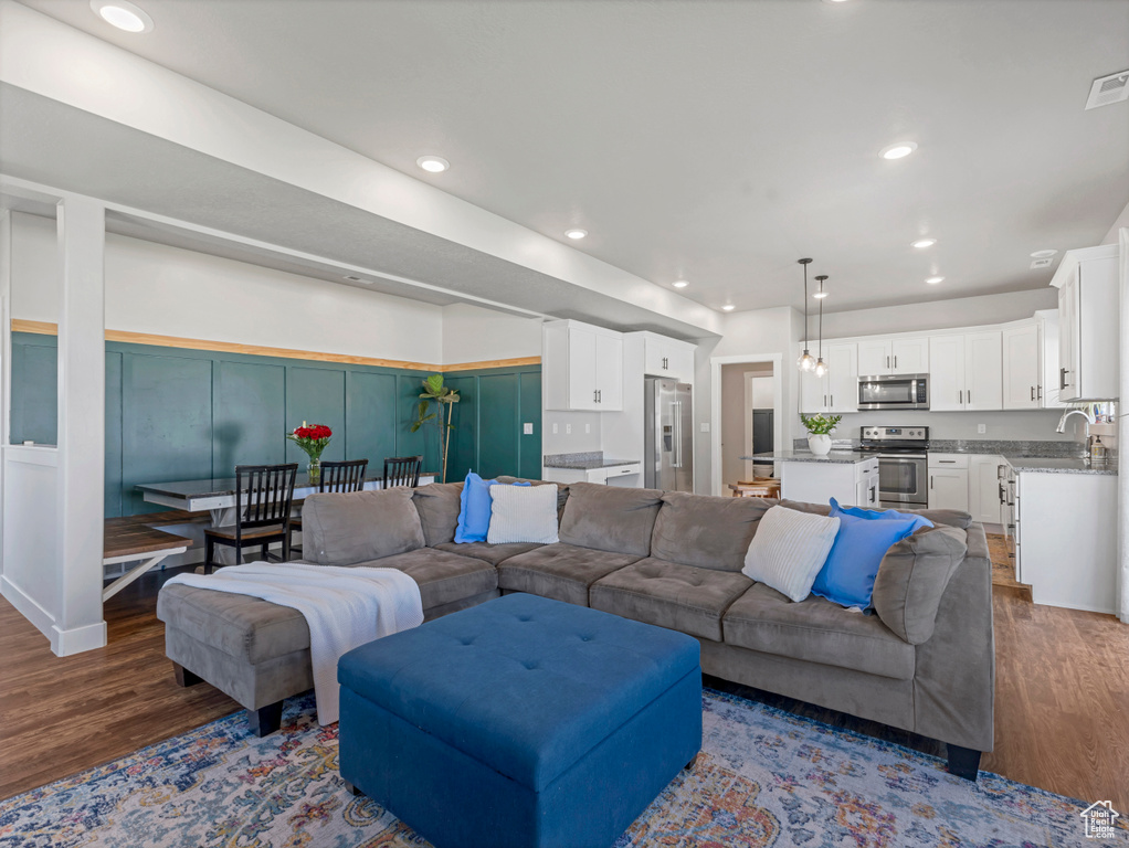 Living room featuring wood finished floors, recessed lighting, a decorative wall, and a wainscoted wall