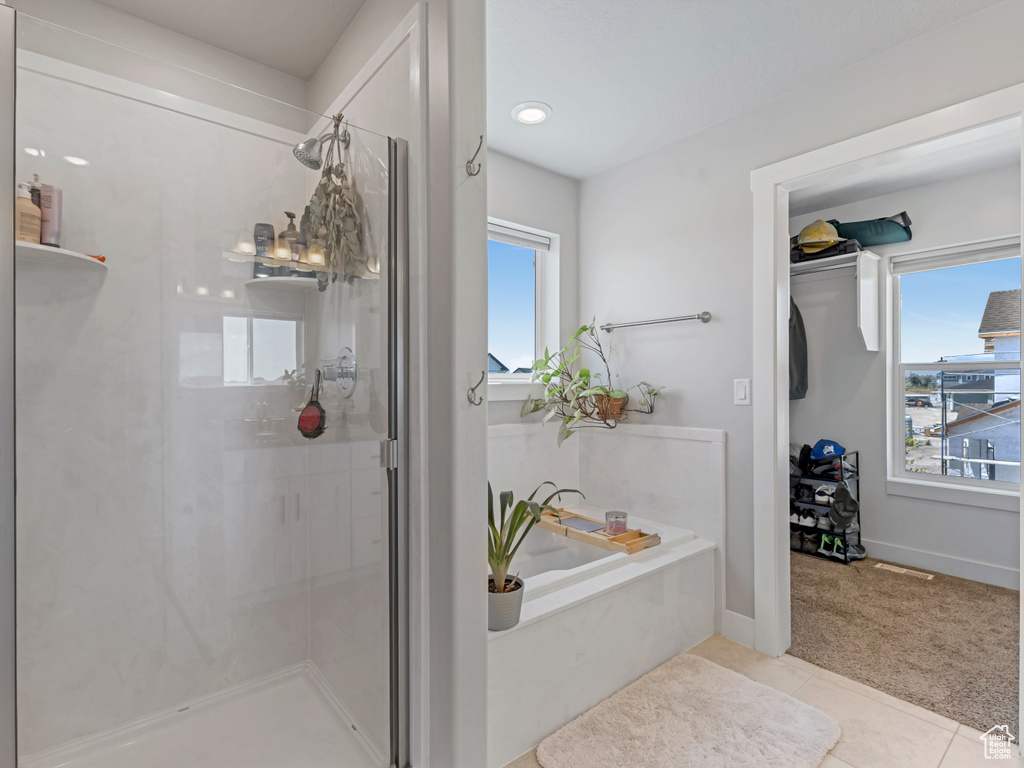 Bathroom with a shower stall, plenty of natural light, a garden tub, and tile patterned floors