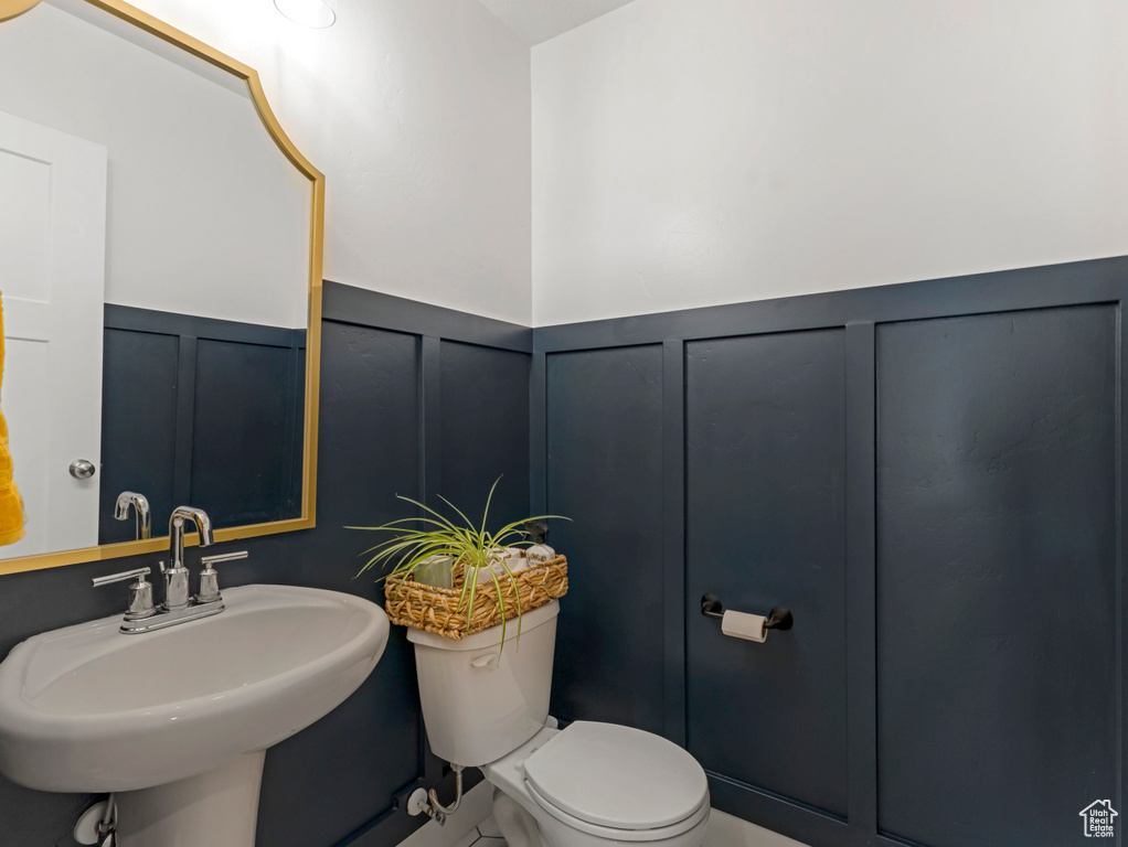 Half bathroom with a decorative wall and wainscoting