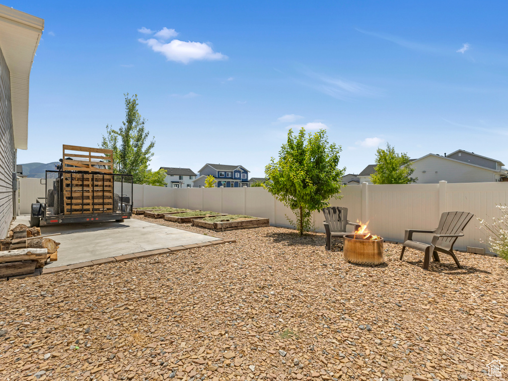 Fenced backyard featuring a patio area, an outdoor fire pit, and a residential view