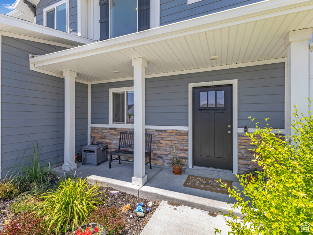 View of exterior entry featuring a porch and stone siding