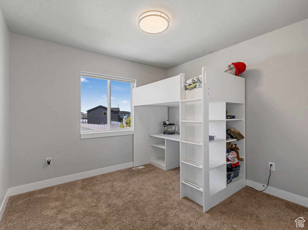 Bedroom with light colored carpet and baseboards
