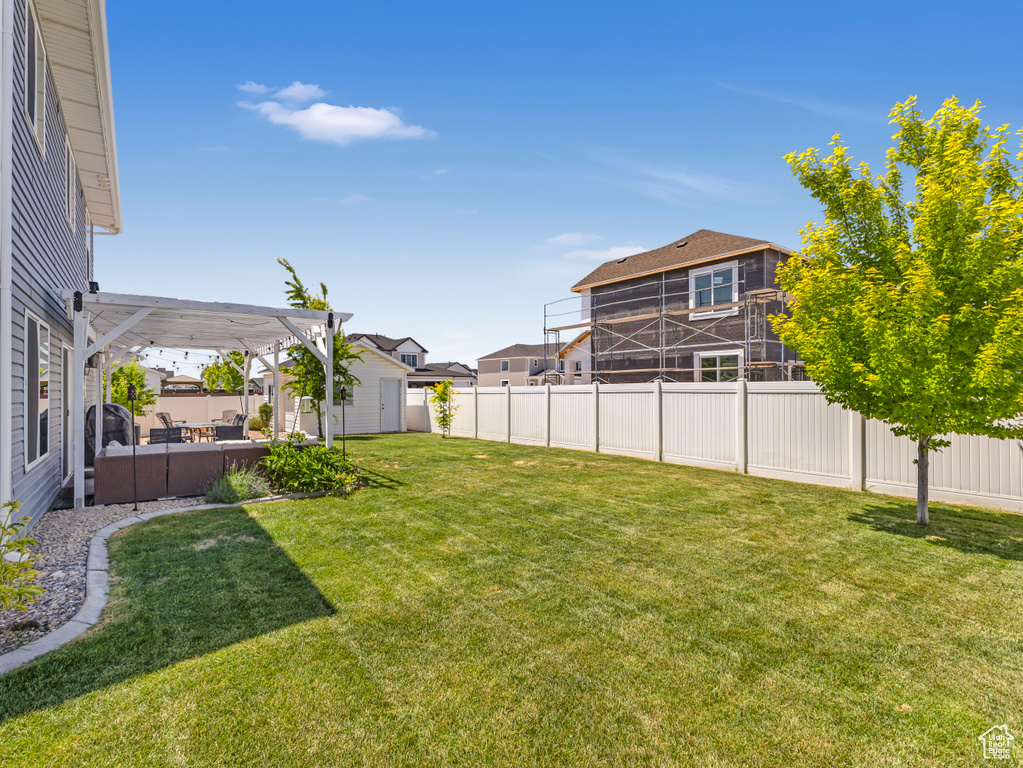Fenced backyard featuring a storage unit, a pergola, an outdoor hangout area, and a residential view